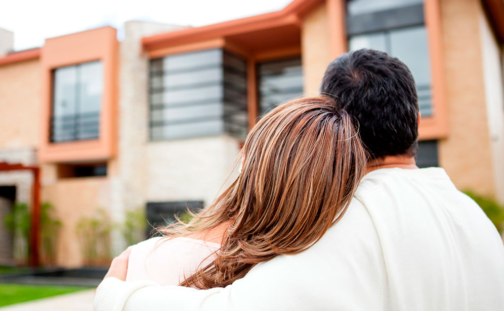 Pareja abrazada viendo un tipo de casa