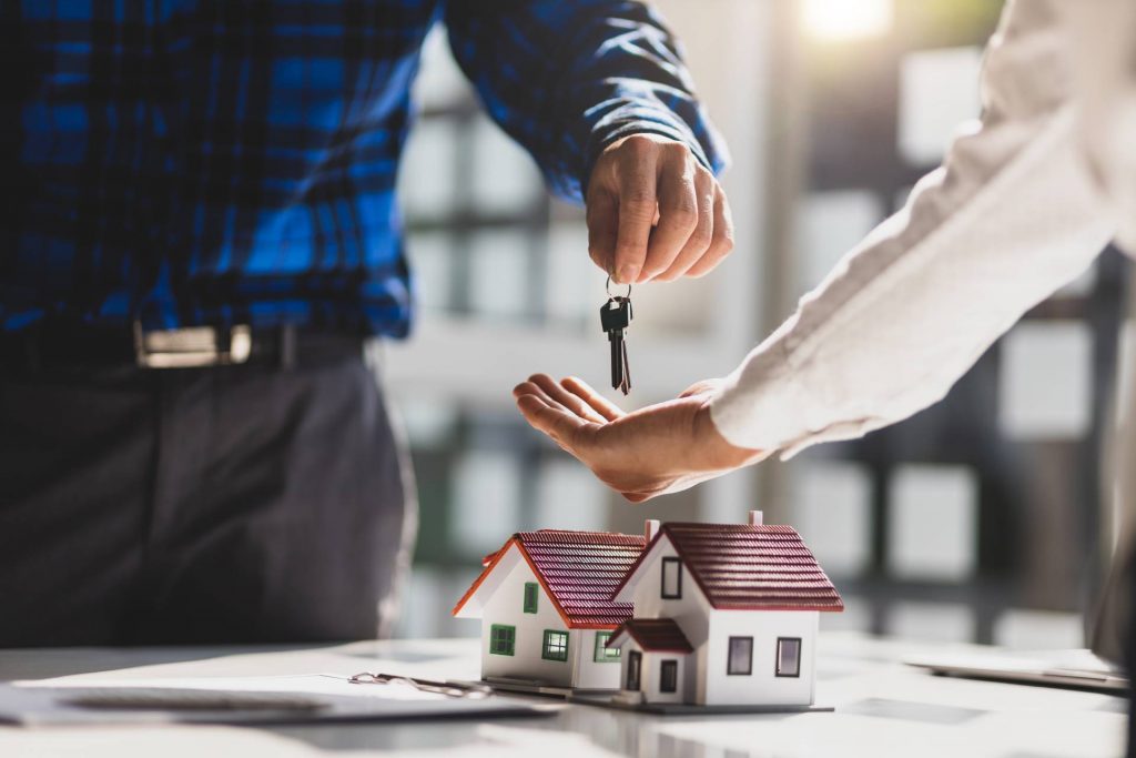 Persona entregando las llaves y un contrato de compraventa de una casa