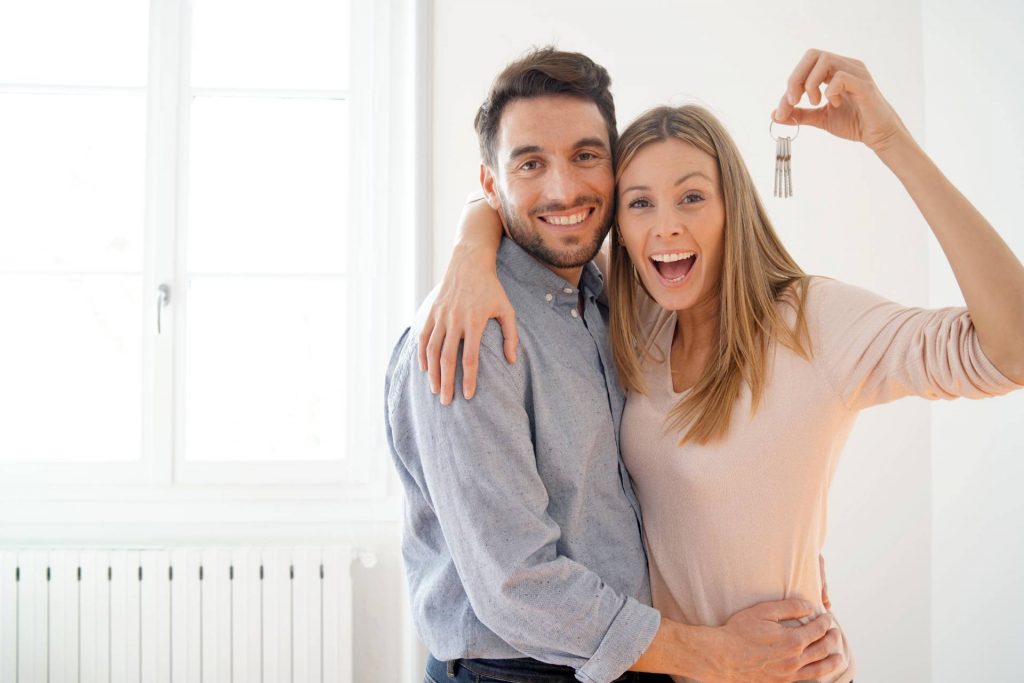 Pareja celebrando la adquisición de un contrato de compraventa de una casa