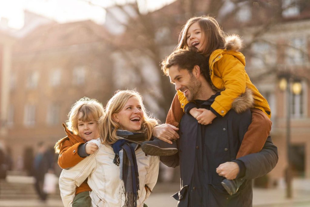 Familia feliz sosteniendo a sus hijos en brazos disfrutando en una de las mejores ciudades para vivir en España