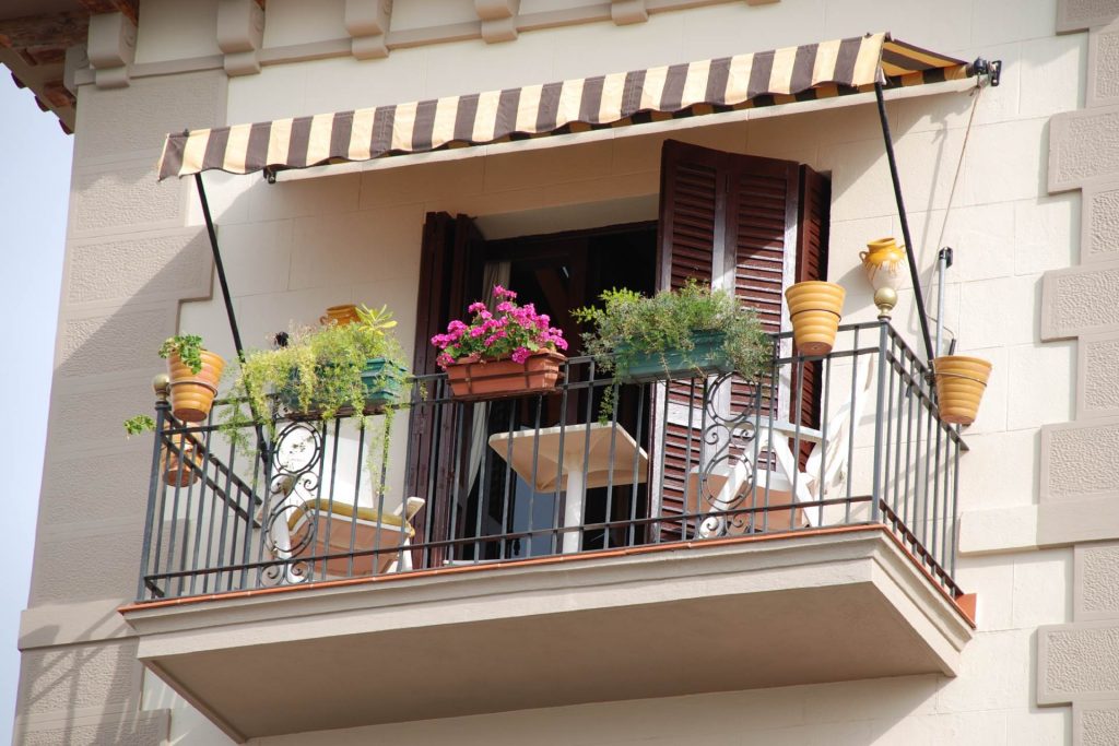 Balcón pequeño decorado con flores, macetas y sillas