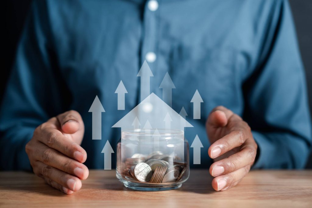 Persona rodeando una hucha con monedas reflejando el ahorro al comprar una casa