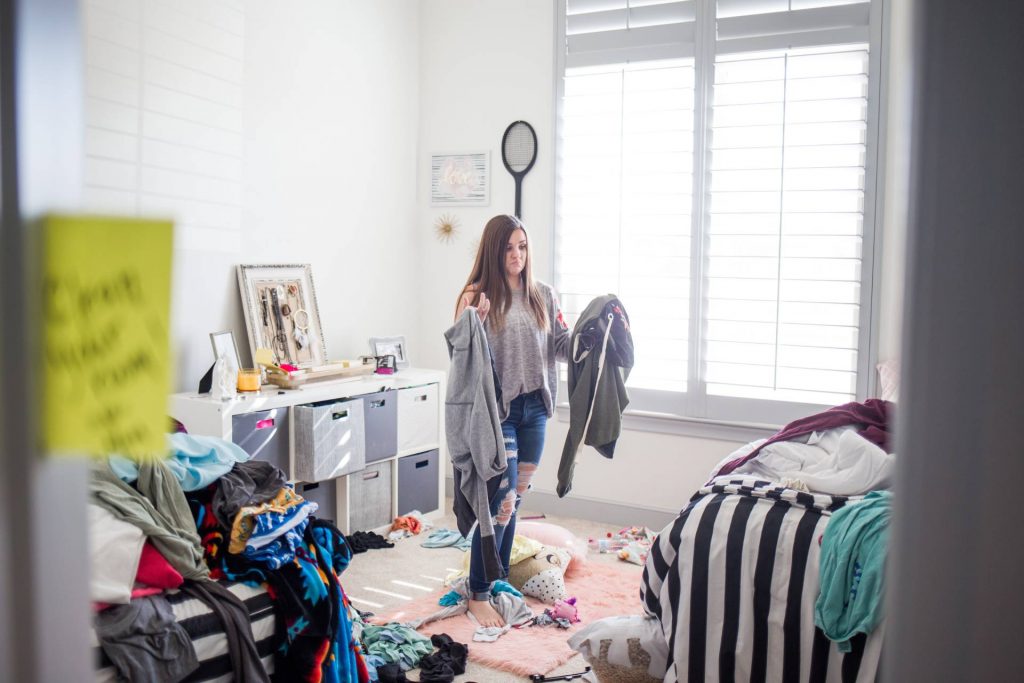 Chica recogiendo las cosas de su habitación desordenada