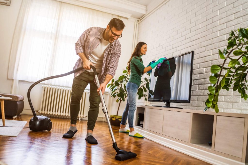 Pareja ordenando y limpiando el salón de su casa