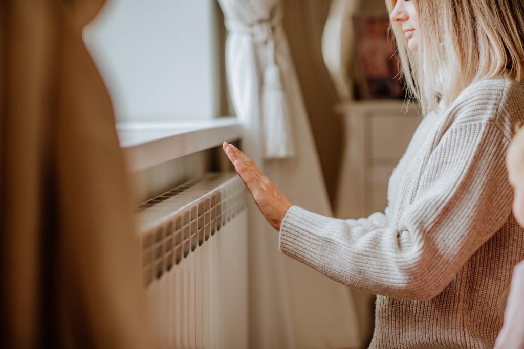 Chica calentándose las manos con al calor del radiador