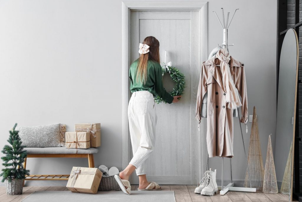 Chica decorando la la puerta de casa de forma navideña 