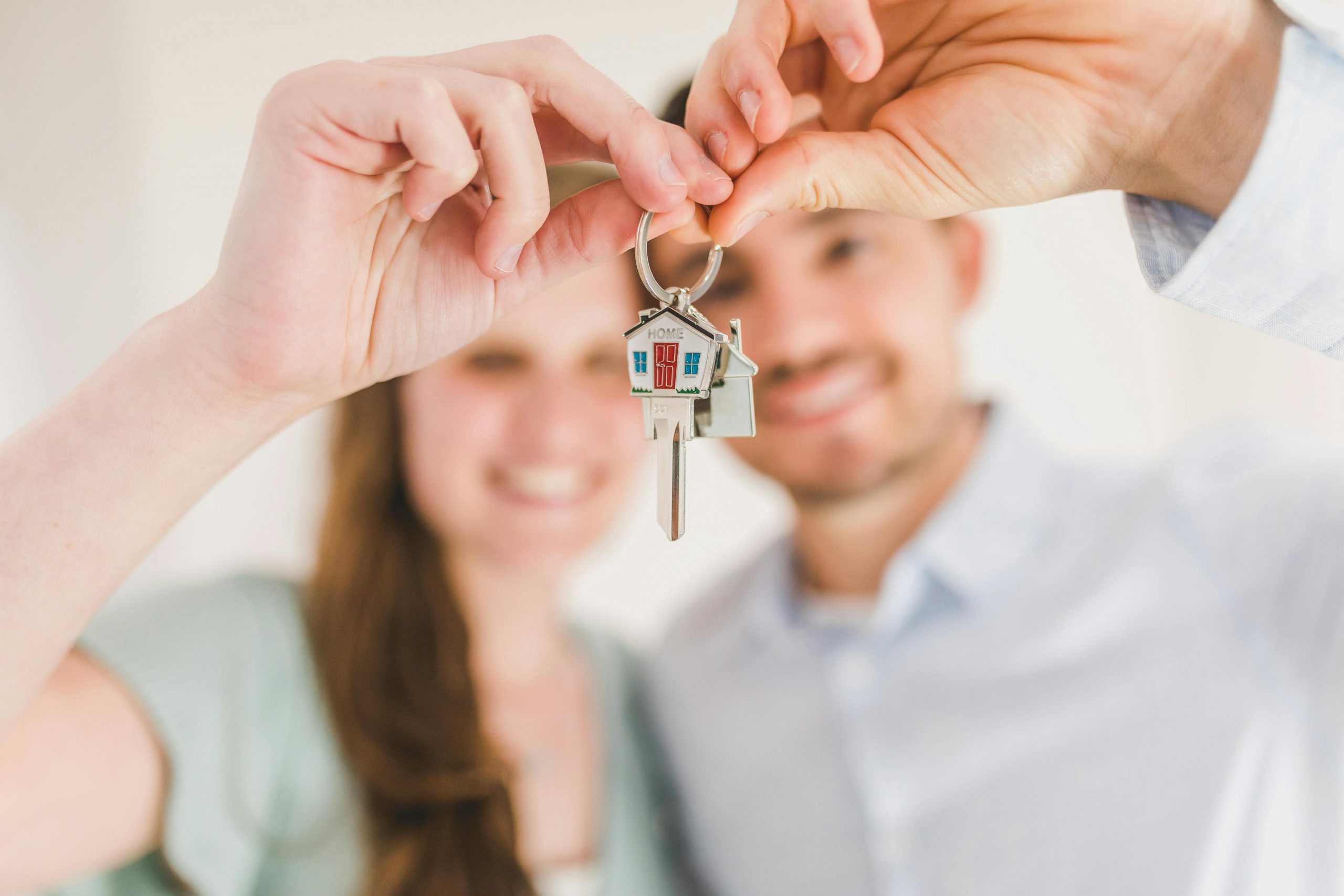 una pareja sosteniendo en sus manos las llaves con un candado de casa