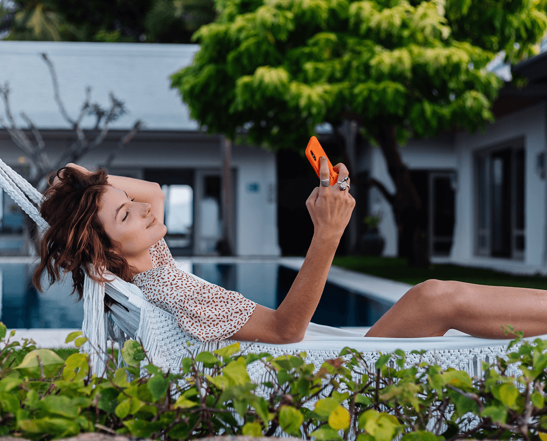 mujer con telefono descansando acostado en una hamaca con telefono movil 1