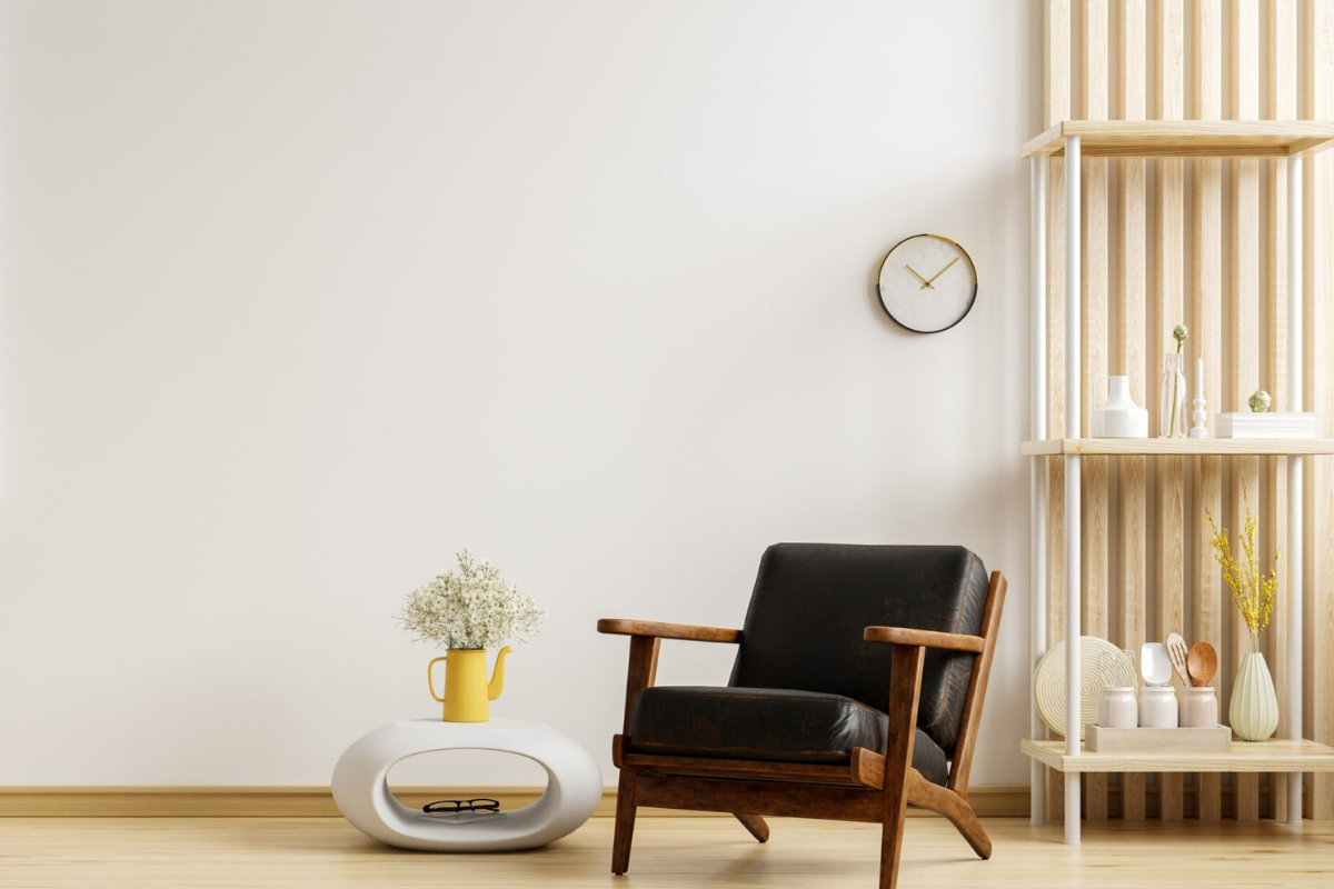 Método Danshari: El arte japonés de ordenar tu casa para liberar tu mente 4 Rincón de lectura minimalista diseñado bajo los principios del método Danshari, con un sillón de cuero oscuro y madera, una mesa auxiliar blanca con un jarrón amarillo y una estantería abierta de madera clara que mantiene pocos objetos para favorecer el orden y la calma mental
